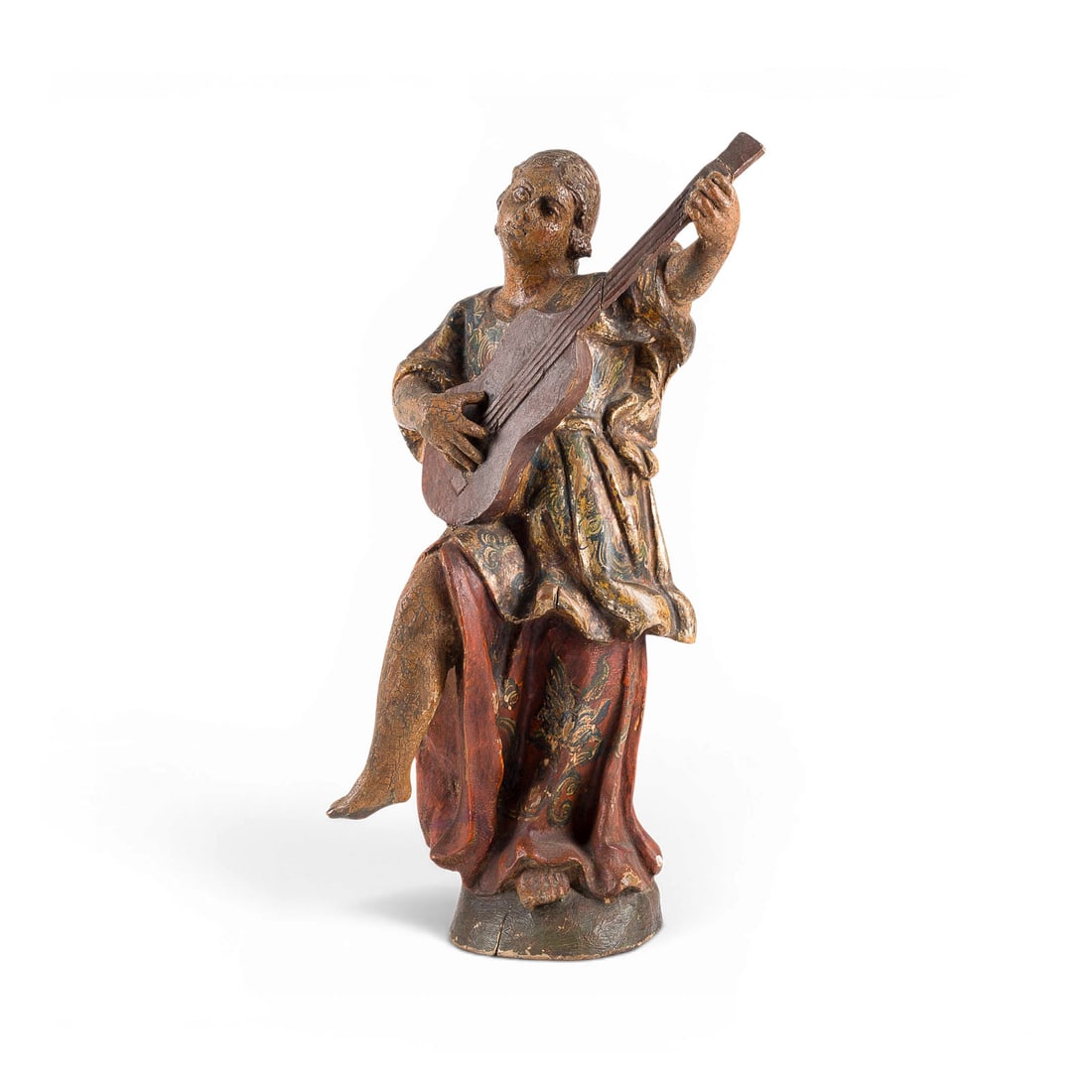 | MUSIZIERENDER BAROCKENGEL MIT ZUPFINSTRUMENT: BAROQUE ANGEL MUSICIAN WITH PLUCKED STRING INSTRUMENT Spain, first half of the 18th century Wood, carved in the round, polychrome finish, and richly gilded. H. 50, W. 26, D. 17 cm. Depiction of an