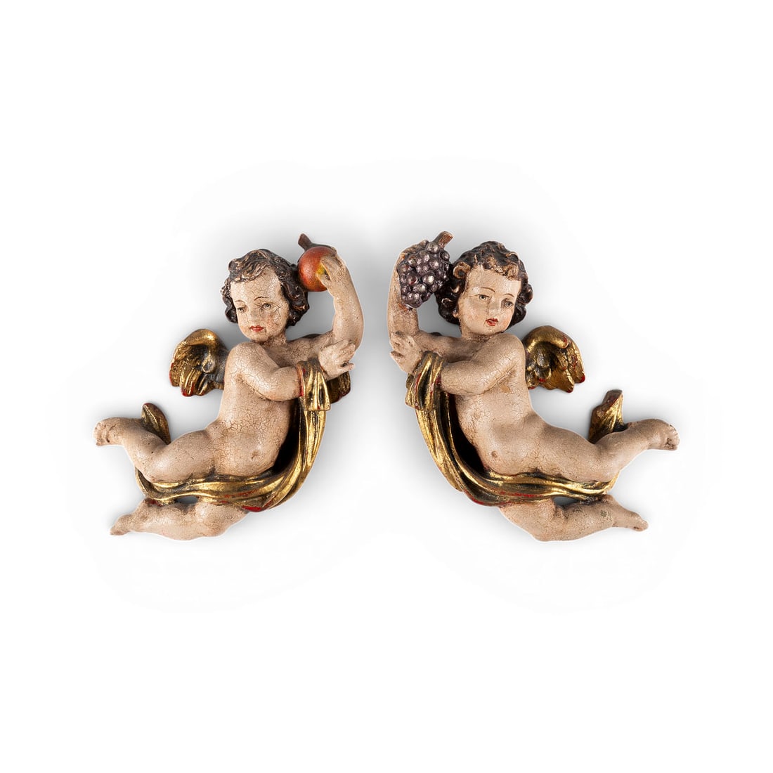 | PAAR GEFLUeGELTE SCHWEBENDE PUTTENFIGUREN: PAIR OF FLOATING WINGED PUTTI Alpine region, circa 1800 Wood, carved in the round, polychrome-painted and gilded, flattened at the back. H. 10.5 cm each, L. 21 cm, D. 6 cm. Minor damage and losses to