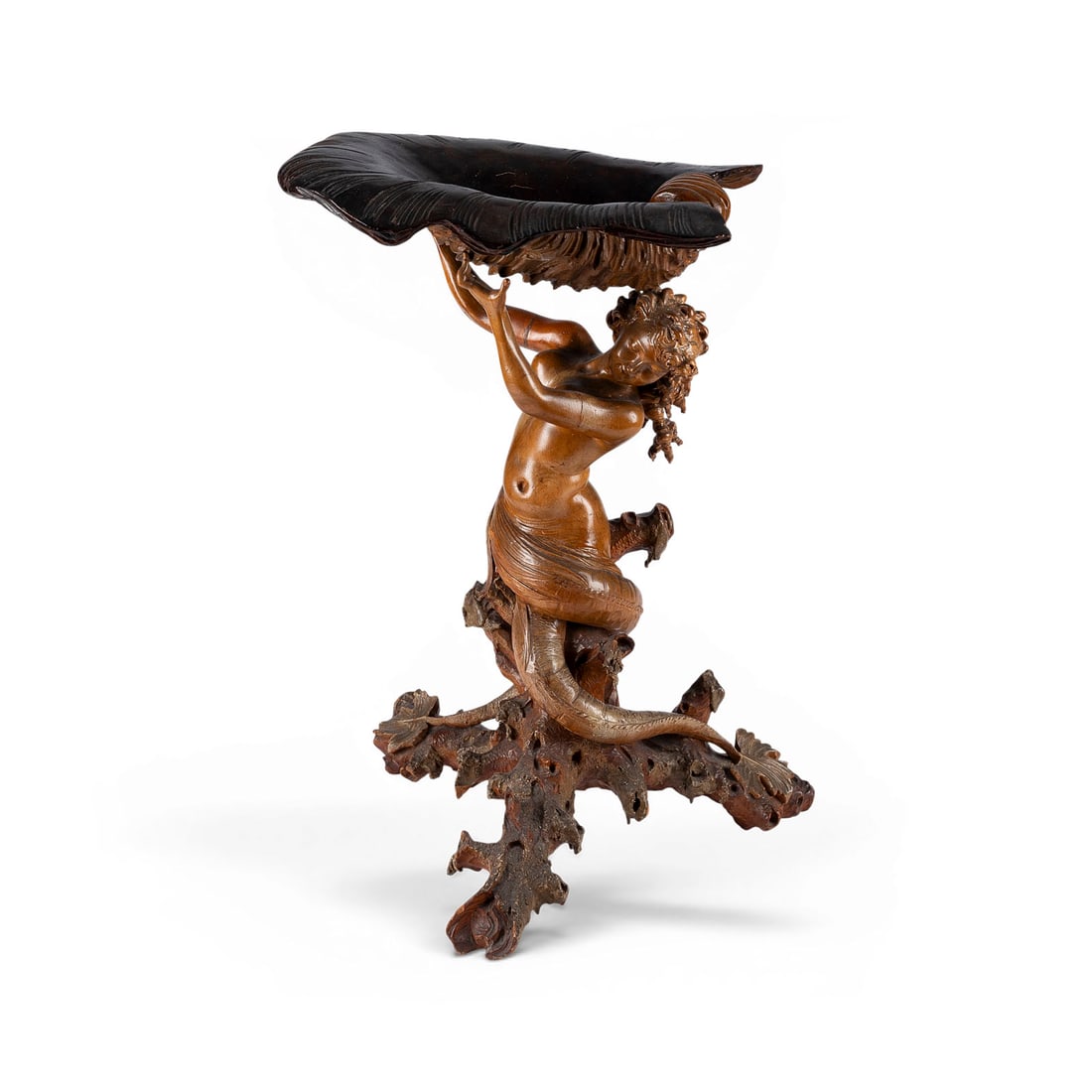 | DAPHNE / NYMPHE ALS KARYATIDE: DAPHNE / NYMPH AS A CARYATID Walnut, fruitwood, and burl wood; carved in the round, polished and waxed to a natural finish. H. 67, W. 48, D. 42 cm. Female half-nude figure in the form of a nymph. She