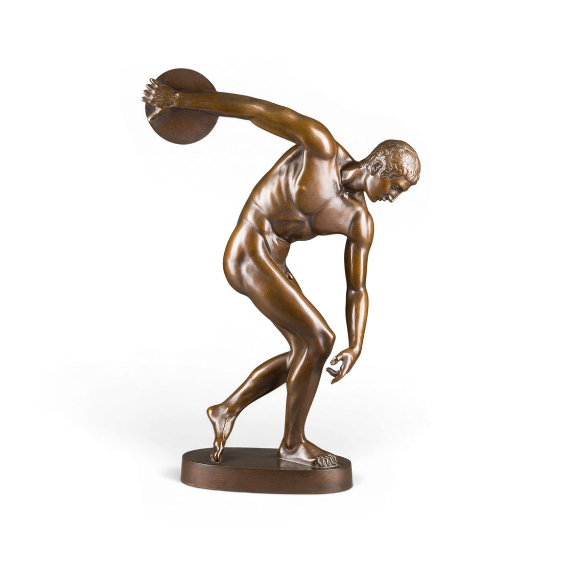 MONOGRAMMIST 'R.S.' | DISKOBOL DES MYRON (NACH ANTIKEM VORBILD): MONOGRAMMIST 'R.S.' Active early 20th century DISCOBOLUS BY MYRON (AFTER AN ANTIQUE ORIGINAL) Bronze, dark patina, on an oval plinth (H. 4 cm). Total H. 58.5, W. 39, D. 15 cm; weight approx. 11.88