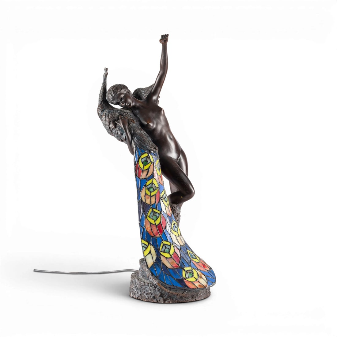 PHILIPPE WOLFERS | NYMPHE UND PFAU ALS TISCHLAMPE: PHILIPPE WOLFERS 1858 Belgium - 1929 (after) NYMPH AND PEACOCK TABLE LAMP Dark-patinated bronze and colored leaded glass, on a rock-like base. H. 67, W. 26, D. 34 cm. Marked 'Philippe Wolfers' on the 