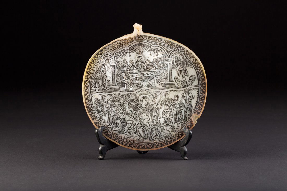 PERLMUTT-IKONE: A MOTHER OF PEARL ICON Jerusalem School, circa 1900 A finely engraved mother of pearl shell with images of the Last Supper in the upper row and the Adoration of the Magi in the lower part. The rim min