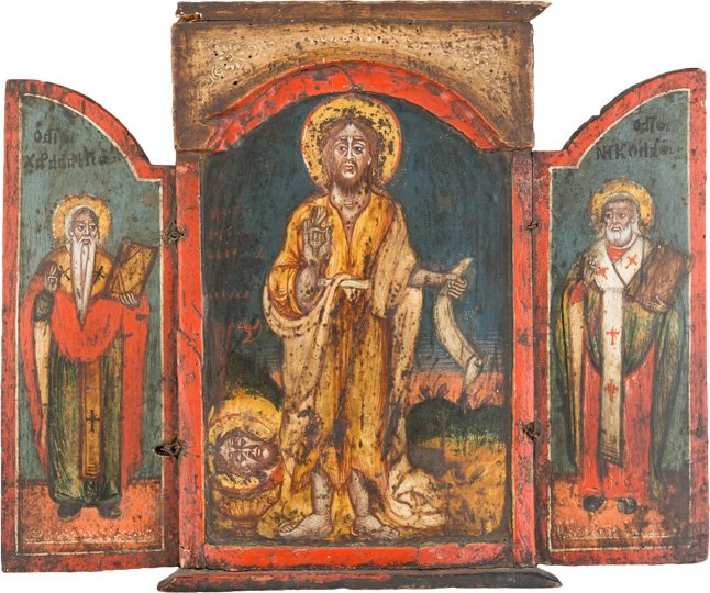 TRIPTYCHON: A TRIPTYCH Greek, 18th century Tempera on wood panel. The central panel showing St. John the Forerunner holding an open scroll. The wings illustrating St. Haralambos and St. Nicholas of Myra in bischo