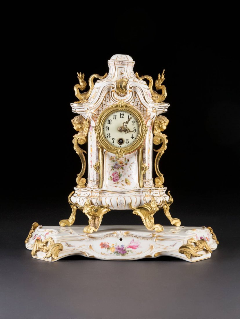 PORZELLANUHR 'LENZKIRCH' Deutsch, KPM Berlin u.a. um: PORZELLANUHR 'LENZKIRCH' Deutsch, KPM Berlin u.a. um 1900 Porzellan, polychrome Malerei, Goldstaffage, Messing. H. 35 cm (mit Sockel). Unterglasurblaue Zeptermarke u.a. Pressmarken, Pressnummern. Auf