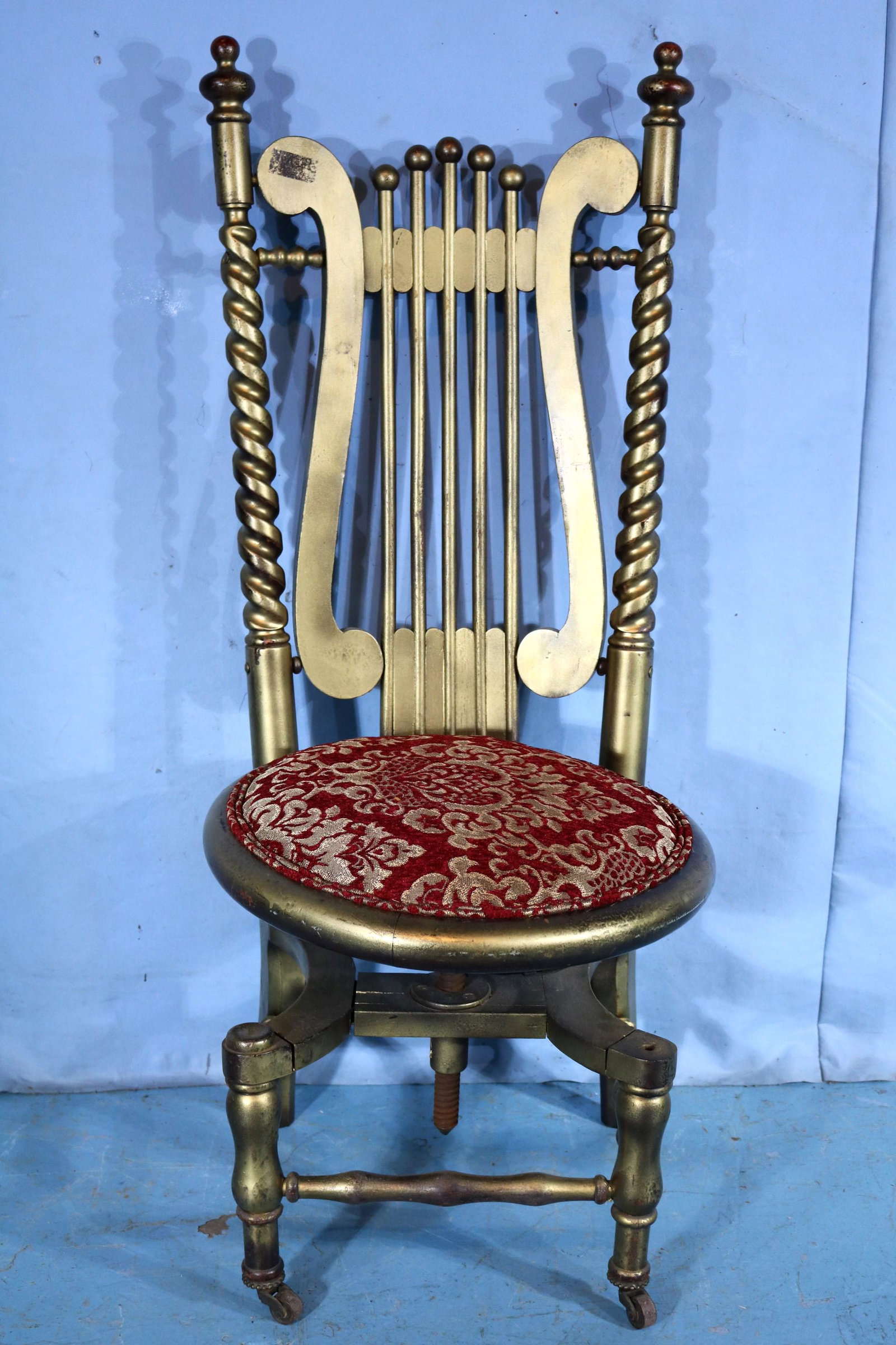 Unusual gold gilded adjustable piano stool: Unusual gold gilded piano stool with adjustable seat and red and gold upholstery, 44 in. T, 19 in. Dia.
