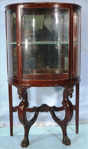 Mahogany curio cabinet with carved lion heads: Mahogany curio cabinet with carved lion heads, curved front and legs, 55 in T, 31.5 in. W, 15 in. D.