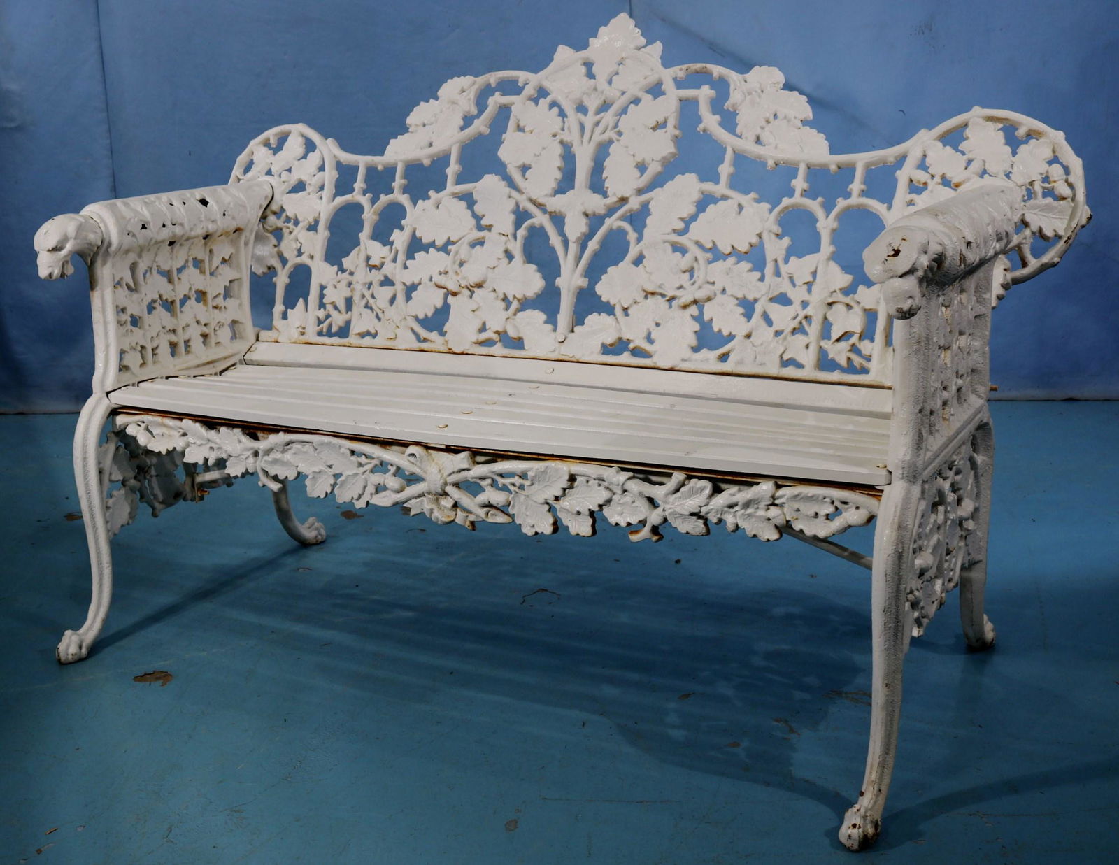 Cast iron garden bench with dog head on round arms: Cast iron garden bench with dog head on round arms, 38 in. T, 67 in. W, 20 in. D.