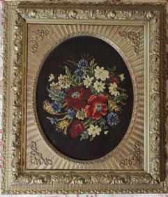 Framed needlepoint of flowers behind glass in old Victorian frame