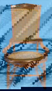 Antique Victorian Caned Rocking Chair with Shaped Arms and Turned Stretchers: Antique Victorian rocking chair featuring a finely woven cane seat and high backrest, framed by a gently arched crest rail with subtle carved detail. The chair’s gracefully shaped arms flow into a s