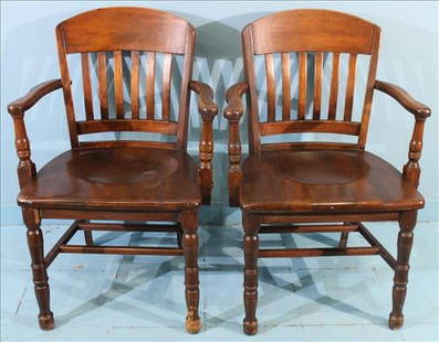 Pair of Vintage Courtroom or Bankers Armchairs with Turned Front Legs: Pair of sturdy early-to-mid 20th century hardwood armchairs, likely maple or oak, featuring curved crest rails, vertical slat backs, and contoured plank seats. Each chair rests on robust turned front