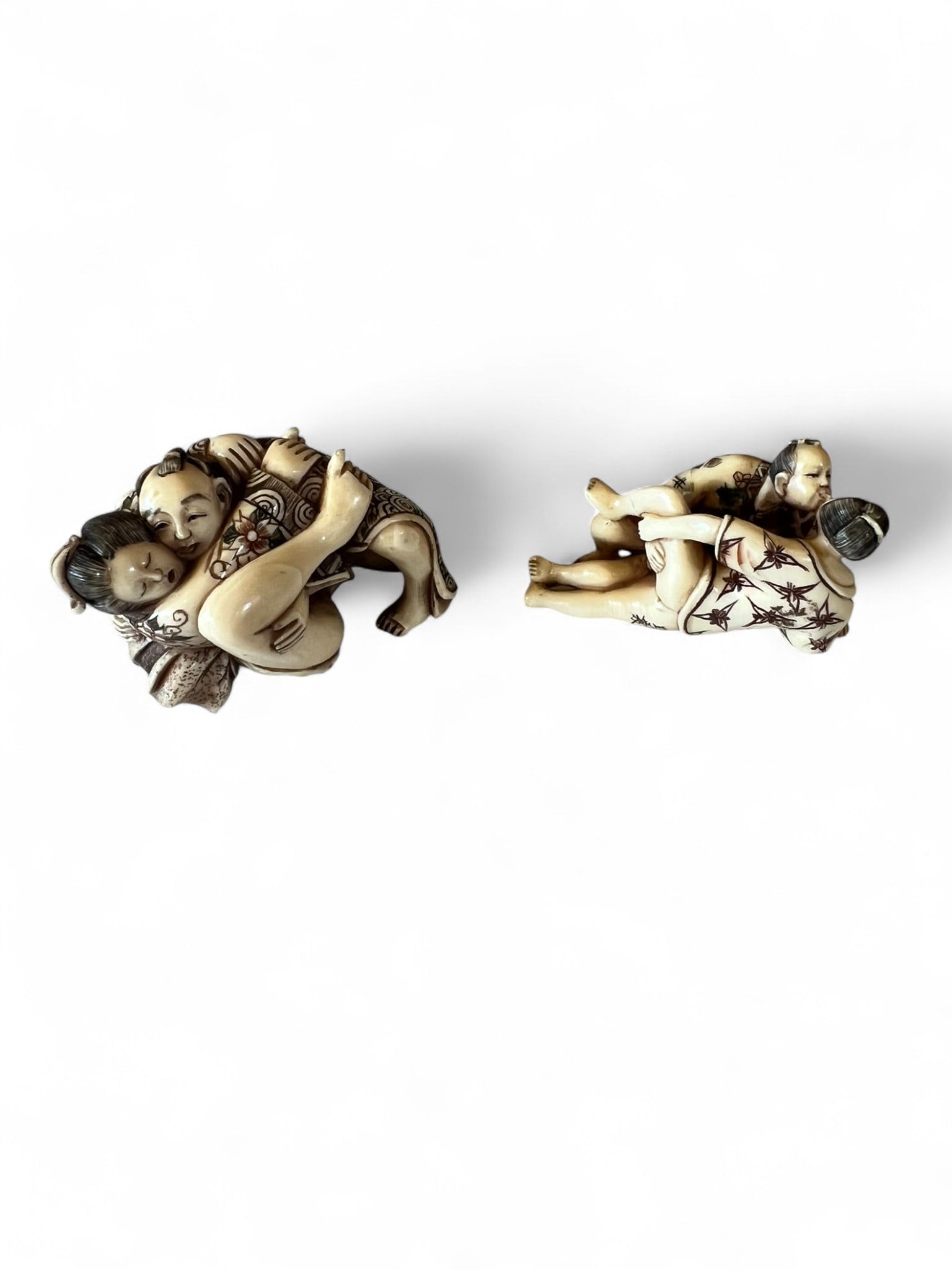 Pair of Japanese Carved Resin or Bone Figural Netsuke: Pair of finely carved Japanese figural netsuke, each depicting reclining couples in close embrace, executed with exceptional detail to hair, robes, and facial features. Each piece shows skillful incis