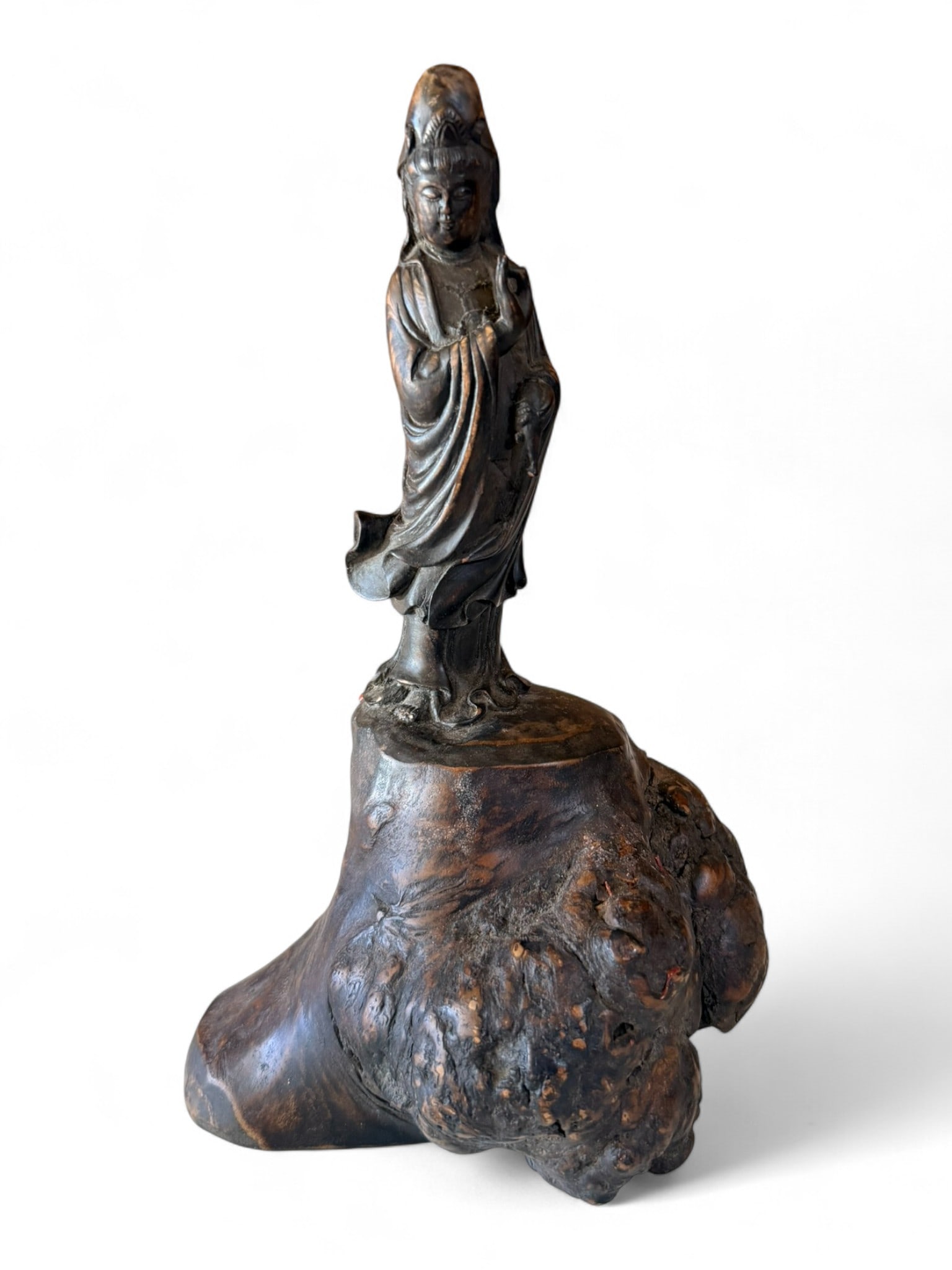 Chinese Bronze Figure of Guanyin on Burlwood Base, Early 20th century: A finely cast bronze figure of Guanyin, the Bodhisattva of Compassion, shown standing in serene pose with flowing robes and downcast expression, mounted on a natural burlwood base with rich grain and