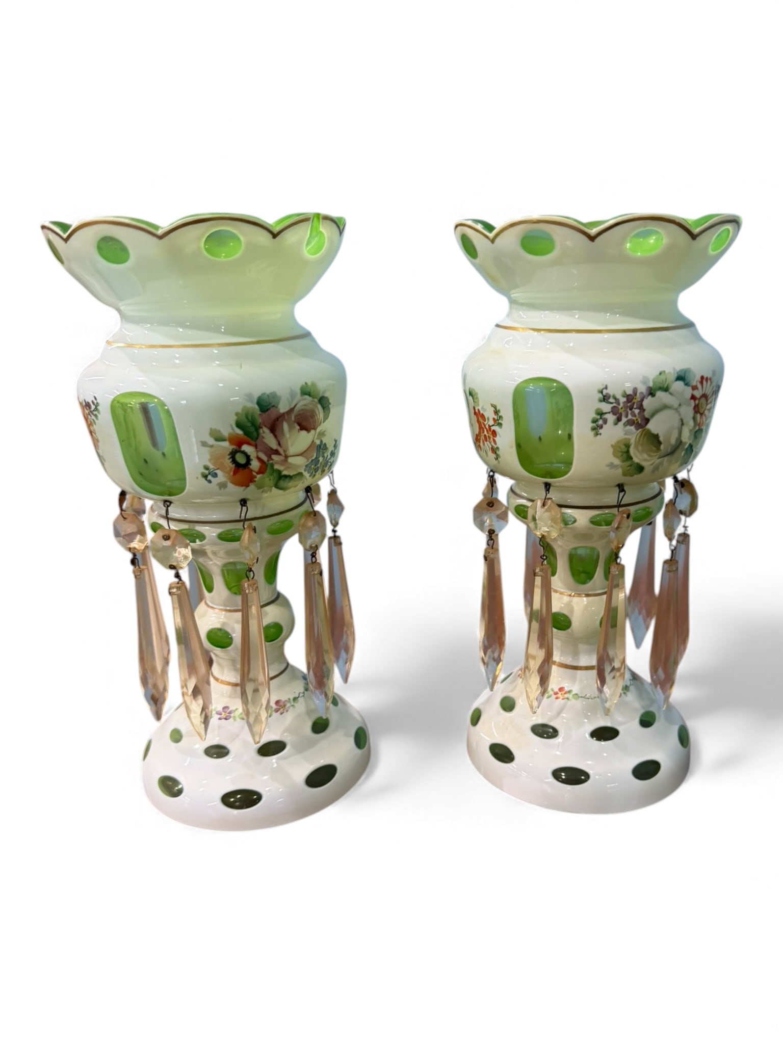 Pair of Bohemian-Style Glass Lustres with Green Overlay and Prisms, late 19th–early 20th century: A decorative pair of Bohemian-style glass lustres, each with scalloped green-overlaid rim, enameled floral decoration, and applied oval cut panels. The bodies are suspended with multiple faceted glass