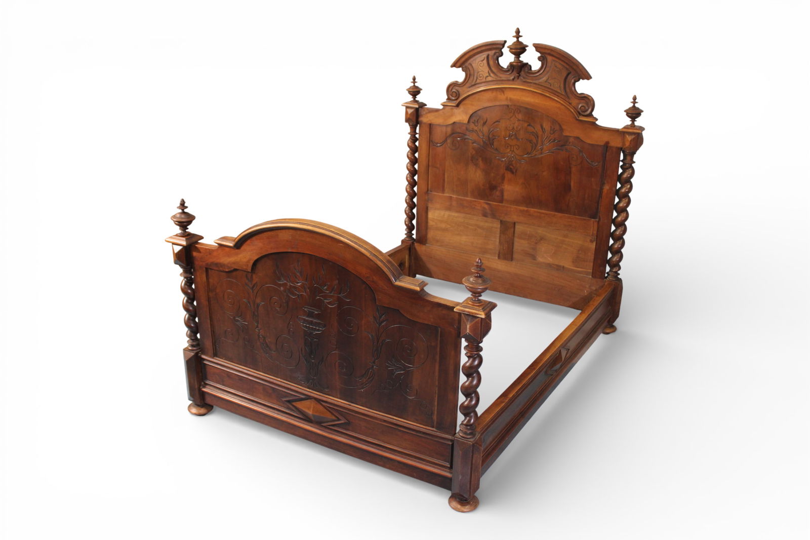 English Victorian Walnut Bed with Barley Twist Posts: English Victorian bedstead in walnut, featuring boldly turned barley twist posts surmounted by urn-form finials. The arched headboard is richly carved with scrolling foliate decoration centering an