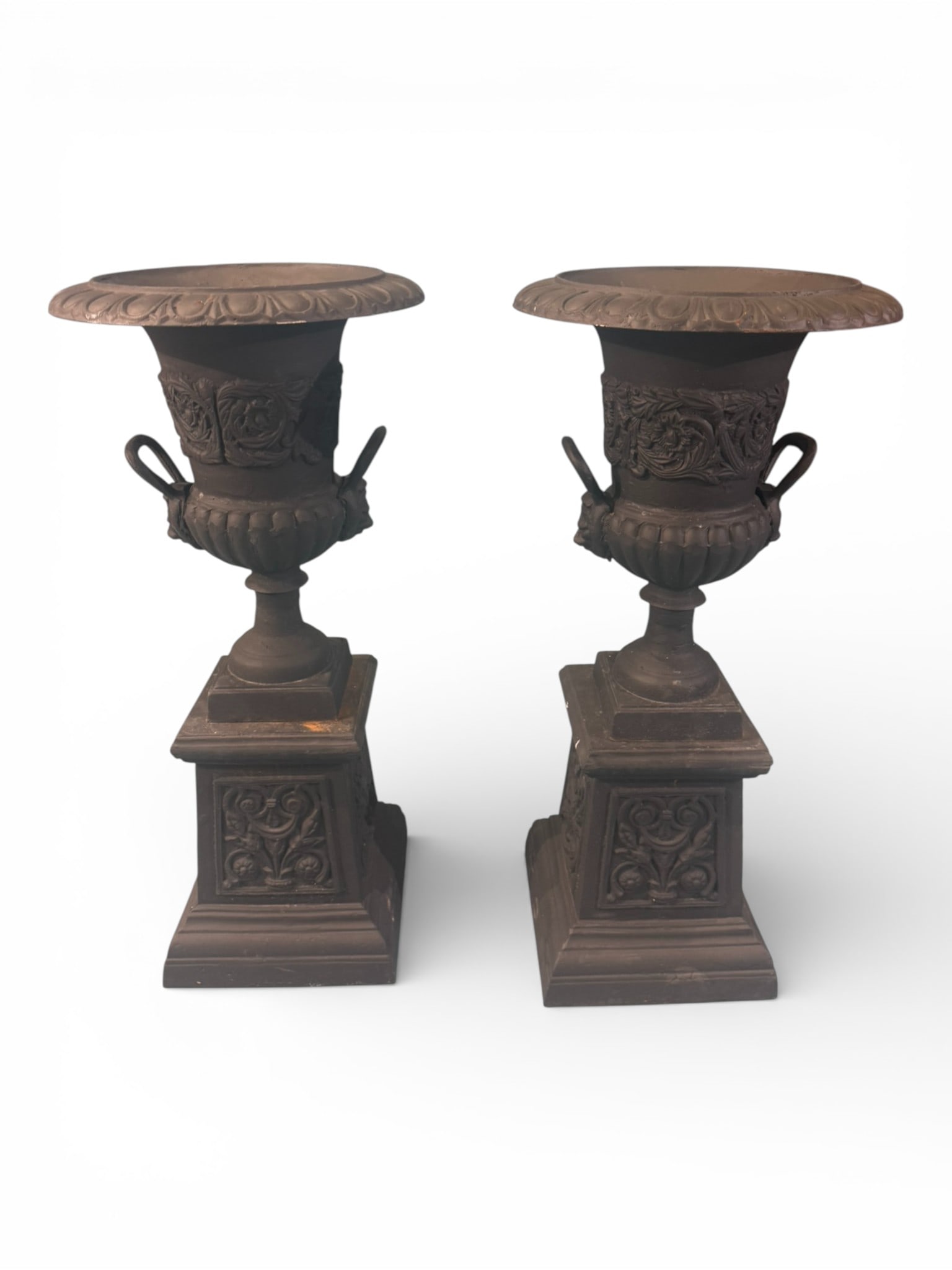 Pair of Large Classical Revival Cast Iron Garden Urns on Pedestals: Impressive and substantial pair of black-painted cast iron garden urns, each of classical campana form with wide gadrooned rim, flared lip, and deeply molded body featuring high-relief foliate and scr