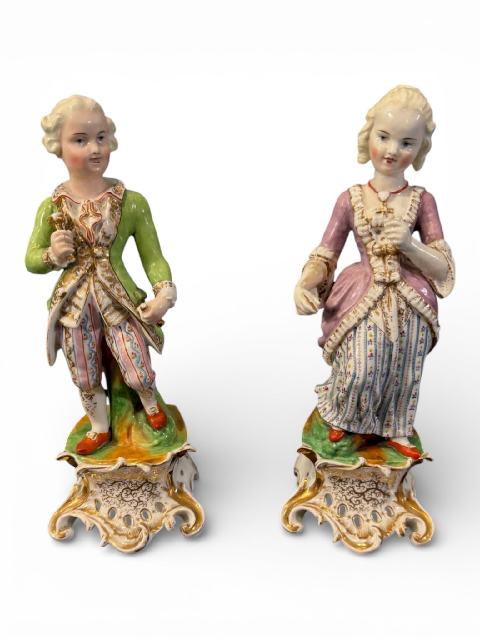 Pair of Continental Rococo-Style Porcelain Figures, 19th Century: A finely modeled pair of Continental porcelain figures depicting an 18th-century gentleman and lady in courtly attire, each standing atop elaborate rococo scroll bases with openwork and gilt