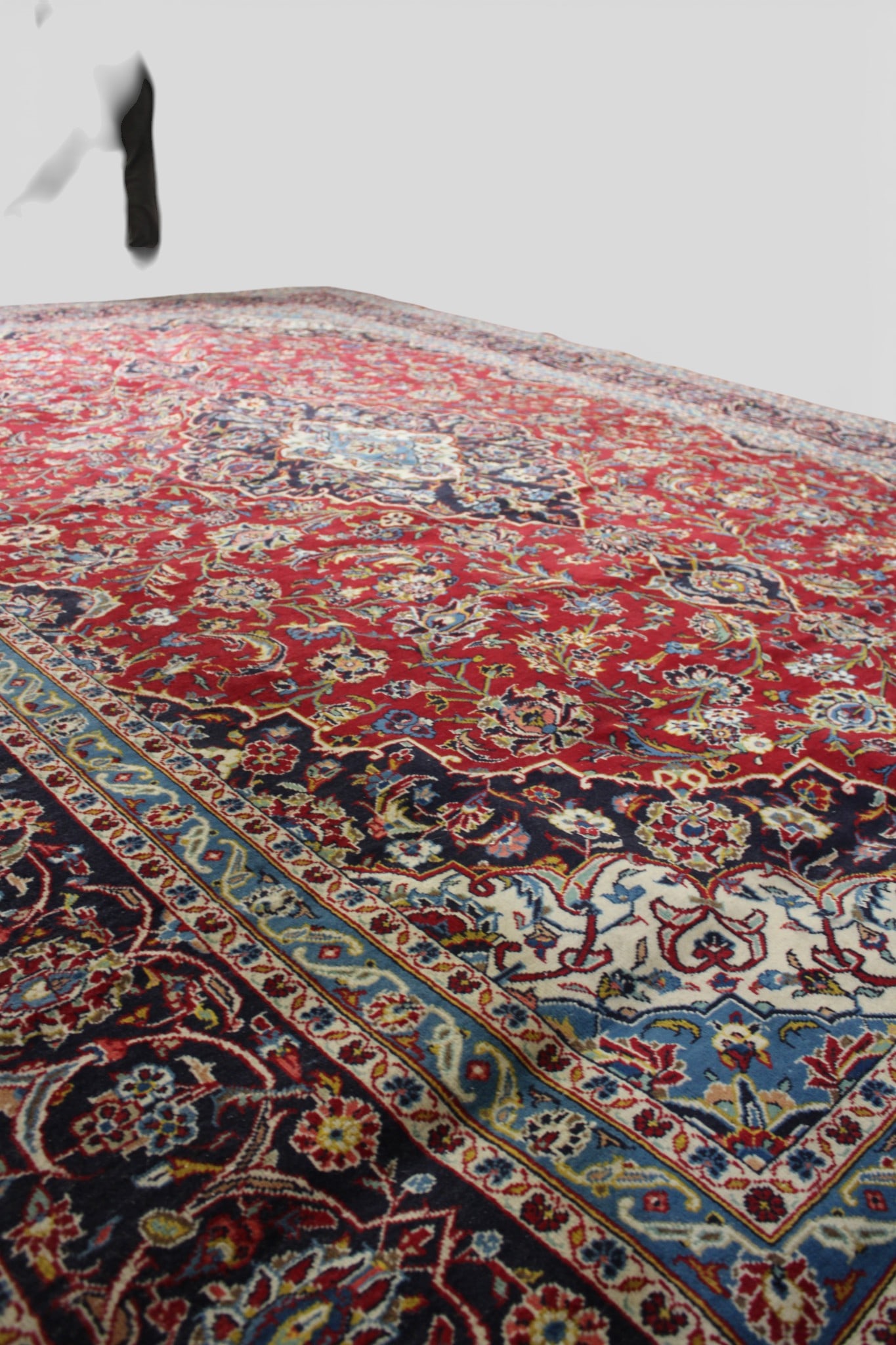 Large Persian Hand-Woven Wool Rug, 20th Century: A large Persian hand-woven wool rug of classic medallion design, featuring a bold central floral medallion set against a rich red field, densely filled with scrolling floral vines and palmettes. The f
