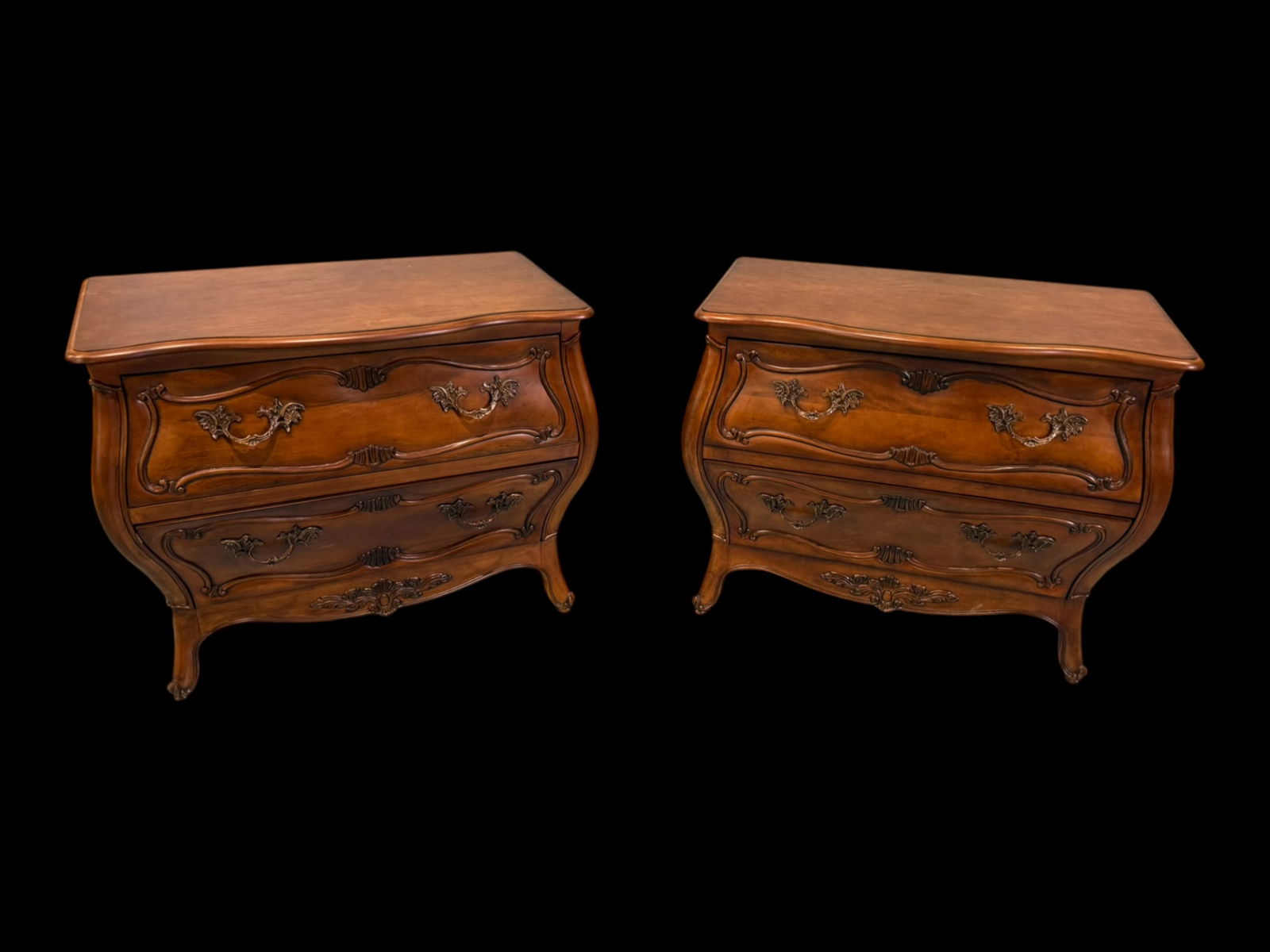Pair of French Provincial Louis XV Style Bombé Commodes, Martel: A handsome matched pair of French Provincial Louis XV–style bombé commodes by Martel, featuring gently serpentine façades fitted with two drawers each. Constructed in stained hardwood with shaped