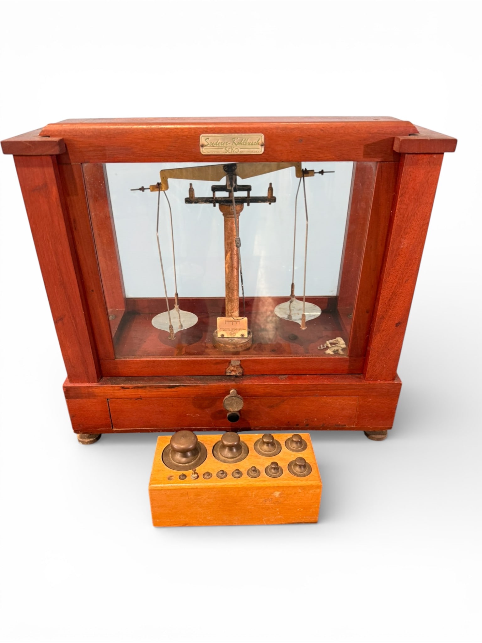 Seeder–Kohlbusch Precision Balance Scale, Early 20th Century: A finely constructed precision balance scale by Seeder–Kohlbusch (SEKO), housed in its original glazed hardwood case with brass fittings. The scale features a central brass column with horizontal