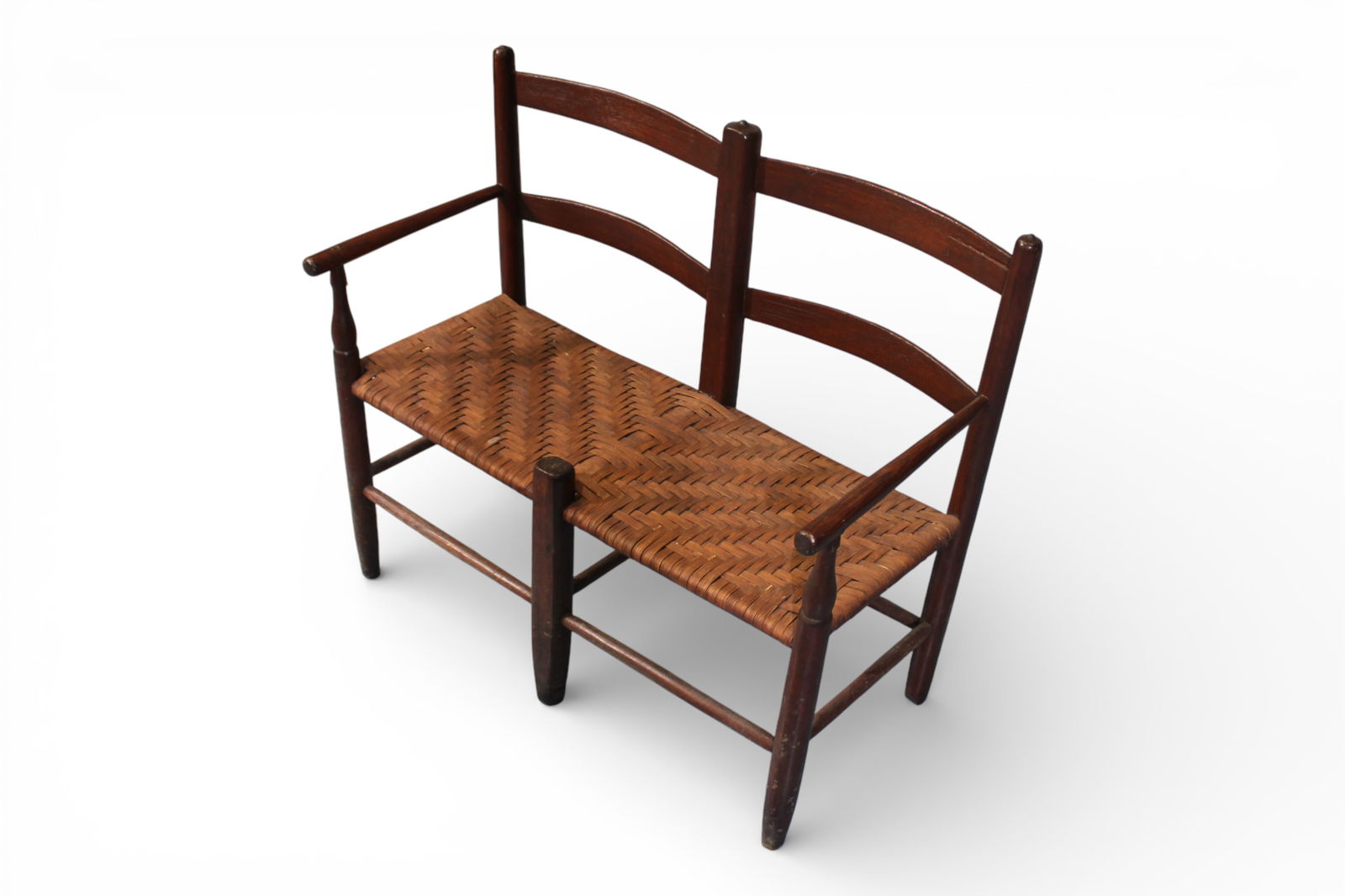 New England Double Slat-Back Settee with Woven Seat: New England country slat-back settee with a gently curved double slat back and woven rush seat, supported on round tapered legs joined by stretchers. The turned arm supports and simple, rustic form