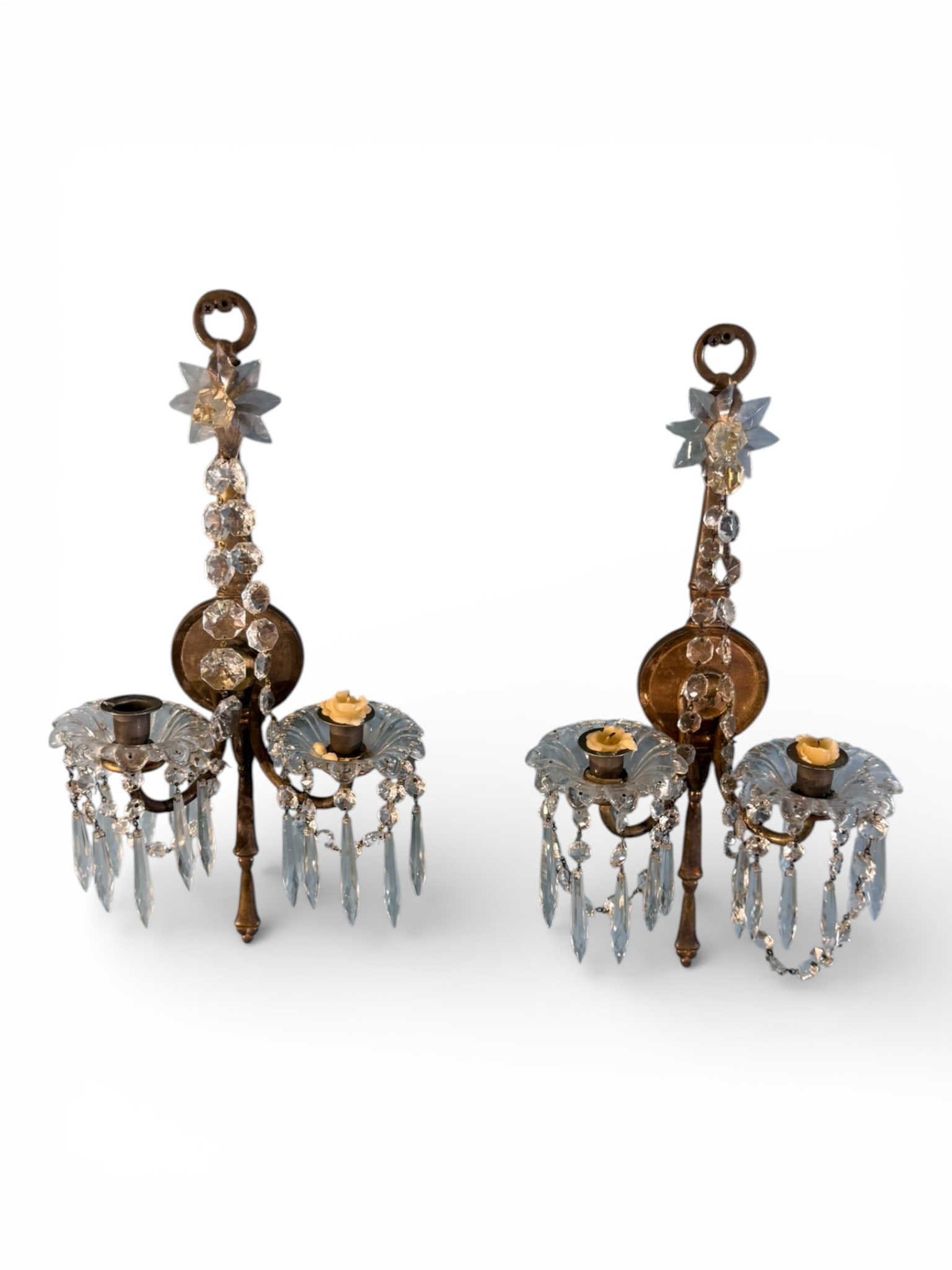 Pair of French Style Gilt Bronze and Crystal Two-Light Sconces: Elegant pair of wall sconces in the French taste, each featuring a gilt bronze backplate surmounted by a crystal starburst finial and ring hanger. The two scrolling candle arms support pressed glass b