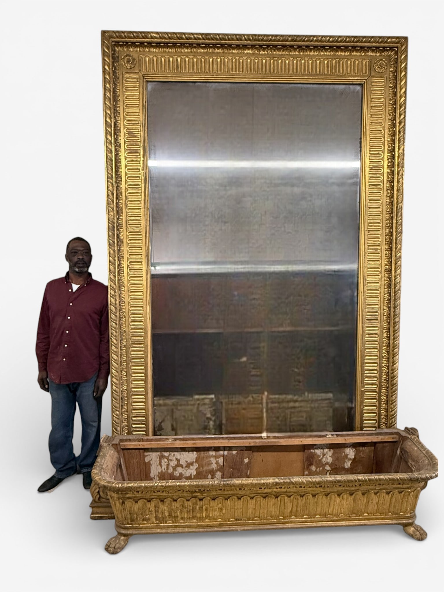 Monumental Giltwood Mirror with Claw Foot Base: An impressive and highly decorative monumental giltwood mirror of classical inspiration, featuring a richly molded rectangular frame with egg-and-dart, beaded, and fluted detailing throughout. The bol