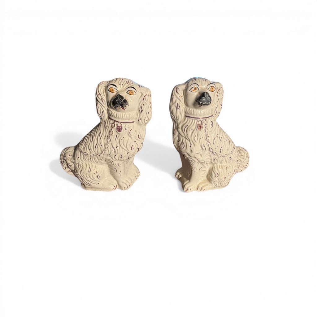 Pair of Staffordshire Pottery Spaniel Figures, 19th Century: A charming pair of 19th century Staffordshire pottery spaniel figures, modeled in the traditional seated form with elongated bodies and expressive faces. Each dog is decorated in a cream ground with h