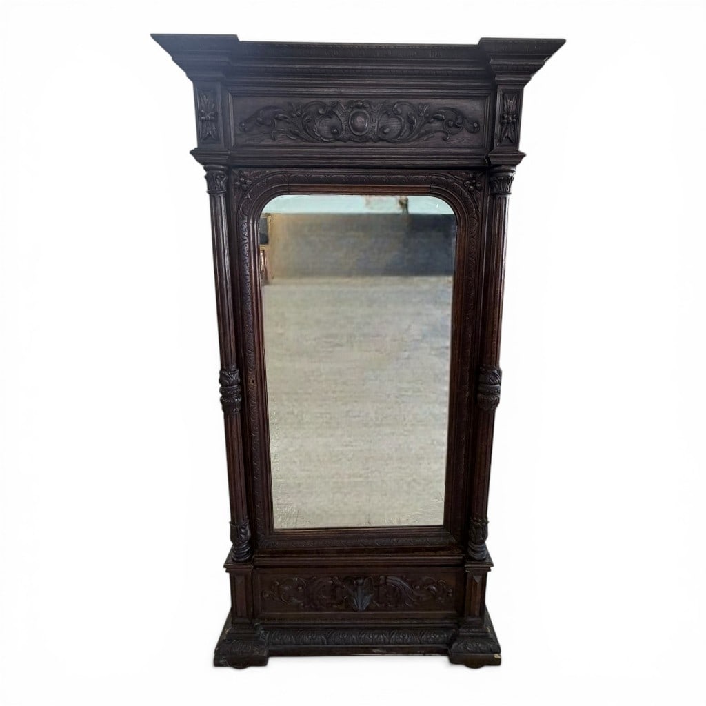 Renaissance Revival Carved Wardrobe with Mirror Door: Renaissance Revival carved wardrobe, late 19th century, featuring a molded and carved cornice with scrolling foliate ornament centered by a cartouche, above a single mirrored door flanked by engaged