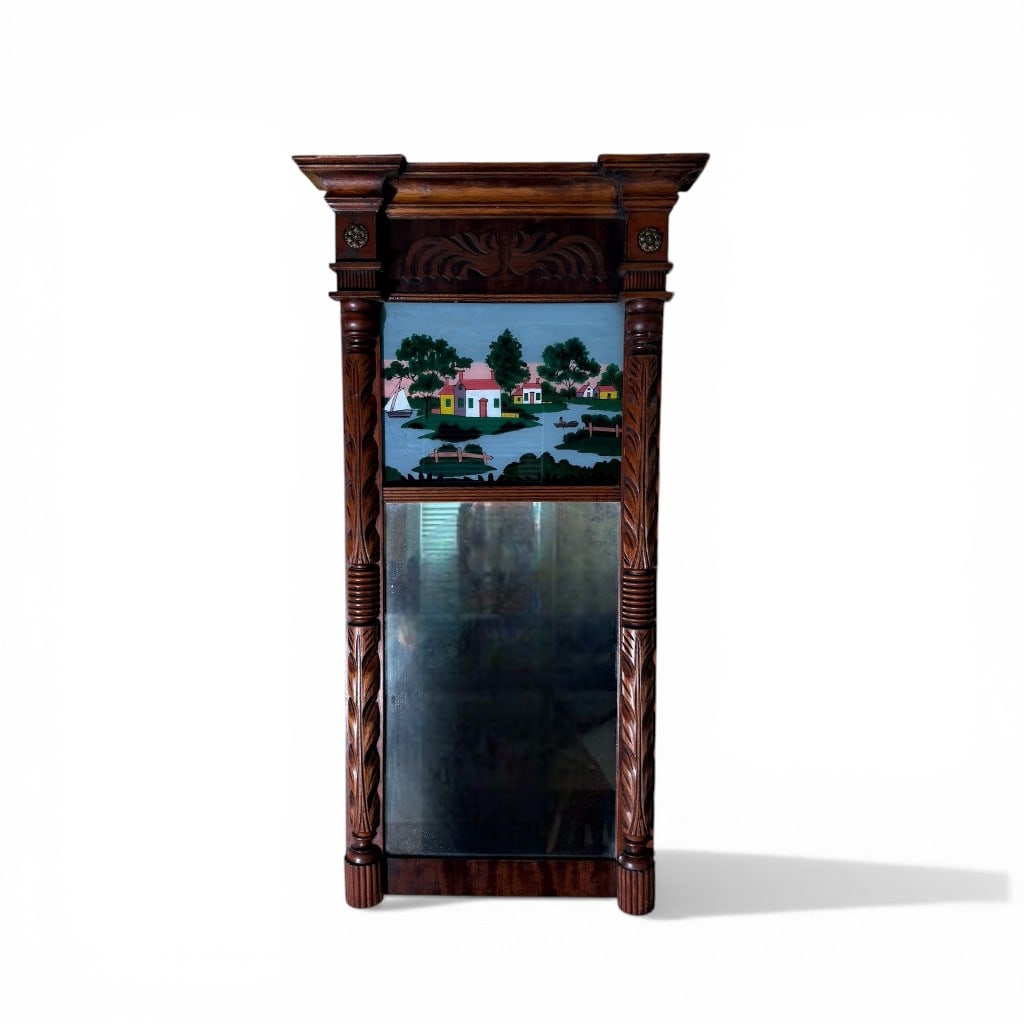 American Empire Églomisé Mirror: A fine American Empire wall mirror featuring a richly figured mahogany frame with bold architectural presence. The molded cornice above a carved frieze with stylized foliate motifs is flanked by proje