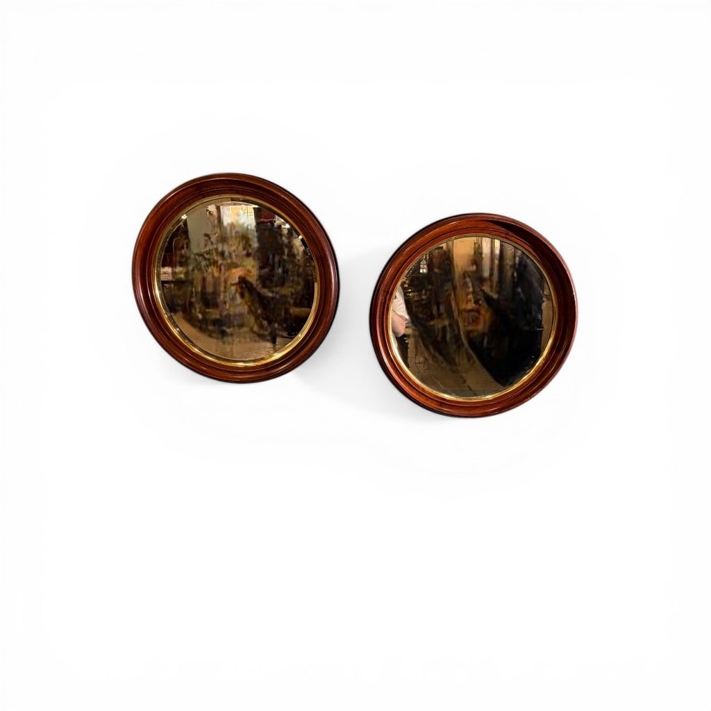 Pair of Convex Wall Mirrors in Wooden Frames: A pair of convex (“bullseye”) wall mirrors, each set within a warm-toned wooden frame with molded edge and gilt inner surround. The mirrors feature domed glass. 22 in. diameter (each)