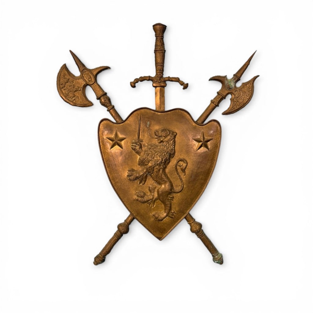 Brass Heraldic Coat of Arms Wall Plaque: A decorative brass heraldic wall plaque in the medieval revival taste, featuring a central shield emblazoned with a rampant lion holding a sword, flanked by two raised stars. The shield is backed by