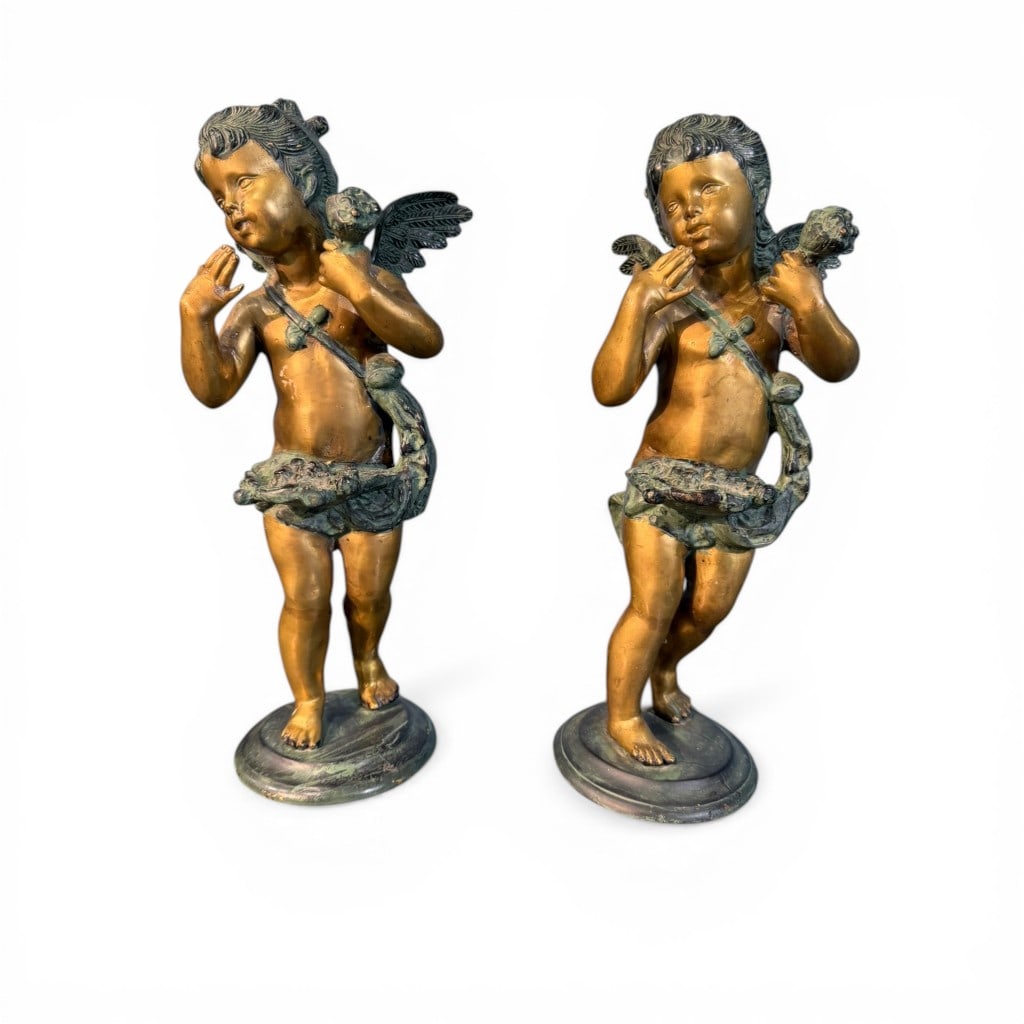 Pair of Gilt Metal Figural Putti Pedestals, John Richard: Pair of cast metal figural pedestals in the form of winged putti, each rendered in a classical pose with draped garlands and verdigris-accented surfaces over a gilt ground. The figures stand atop