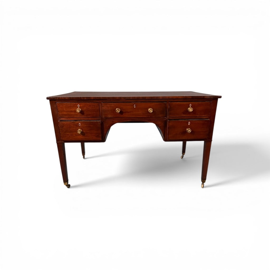 English Regency Mahogany Leather Top Writing Desk: A refined early 19th century English Regency mahogany writing desk, the rectangular top inset with a tooled brown leather writing surface within a crossbanded edge, above a central long drawer