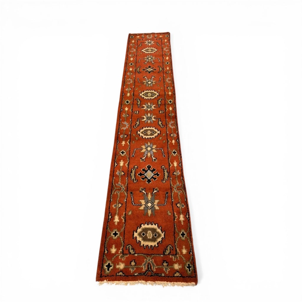 Oriental Wool Runner in Copper and Ivory Tones: A hand-knotted wool runner featuring a warm copper-orange field decorated with repeating geometric medallions and stylized motifs, framed by a complementary border in ivory, charcoal, and muted tones.