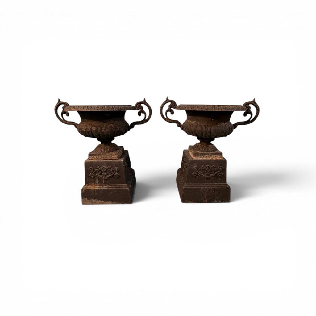 Pair of Classical Cast Iron Garden Urns on Pedestals: A substantial and decorative pair of cast iron garden urns, each of classical campana form with wide flared rims cast in repeating foliate motif, above a lobed body and raised on square pedestal