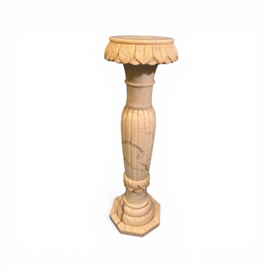 Carved Marble Pedestal with Reeded Column, 20th Century: A marble pedestal crafted in a classical taste, featuring a round top above a carved foliate collar and a tapered, reeded columnar shaft. The stone displays a warm cream tone with natural gray