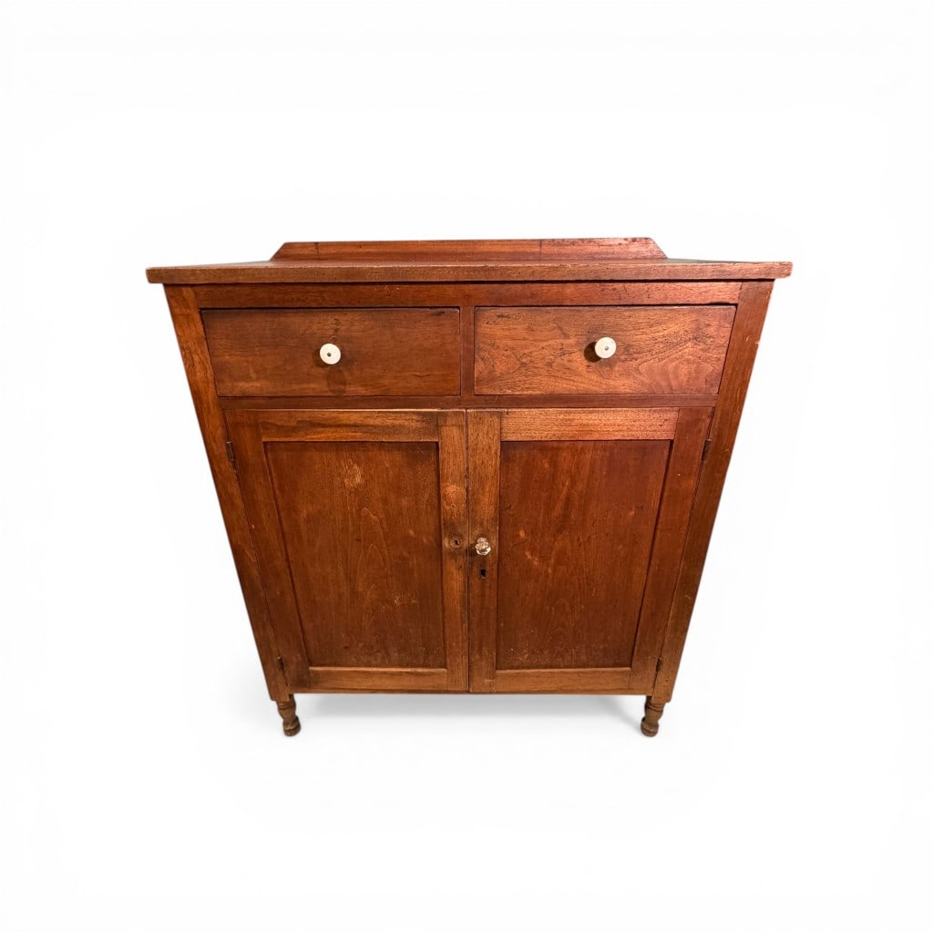 Early American Cherry Washstand, Likely Pennsylvania, Mid-19th Century: A well-proportioned early American washstand crafted in warm-toned cherry, featuring a rectangular top with raised backsplash over two dovetailed drawers fitted with period-style porcelain pulls. The