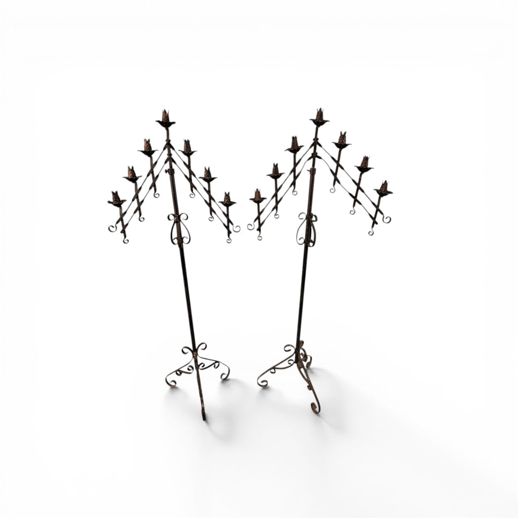 Pair of Wrought Iron Floor Candelabra Stands: Matching pair of tall wrought iron candelabra stands, each featuring a central standard rising to a tiered arrangement of scrolled arms supporting multiple candle cups. The hand-forged construction