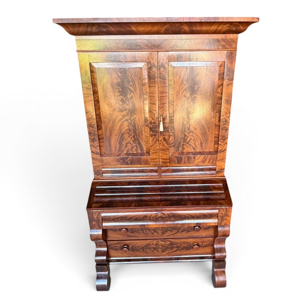 American Empire Flame Mahogany Secretary Bookcase: American Empire secretary bookcase, mid 19th century, in richly figured flame and crotch mahogany veneers, the upper case with bold projecting cornice above two paneled cabinet doors opening to