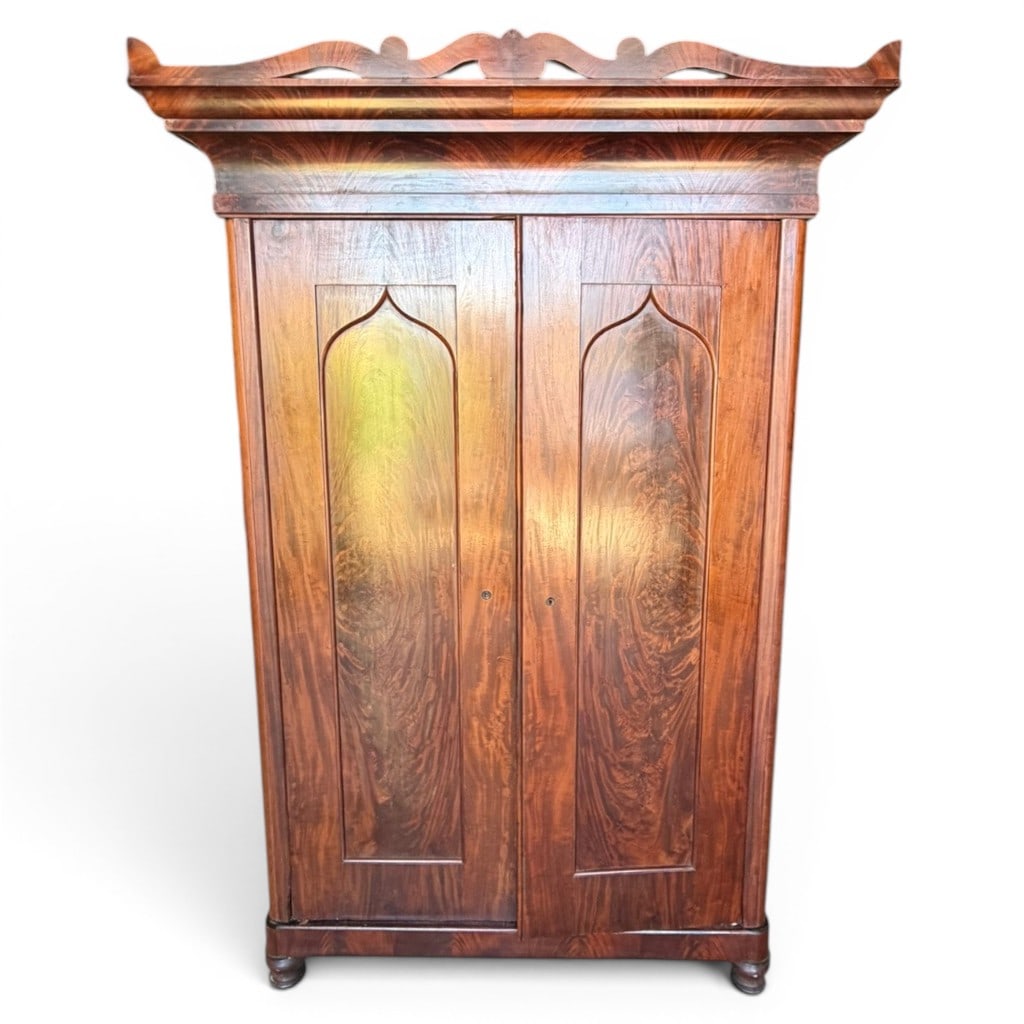 American Empire Gothic Wardrobe: American Empire Gothic wardrobe, circa 1840?1850, in mahogany and mahogany veneers, the tall case with projecting molded cornice above two paneled doors with pointed Gothic-arch panels, opening to a