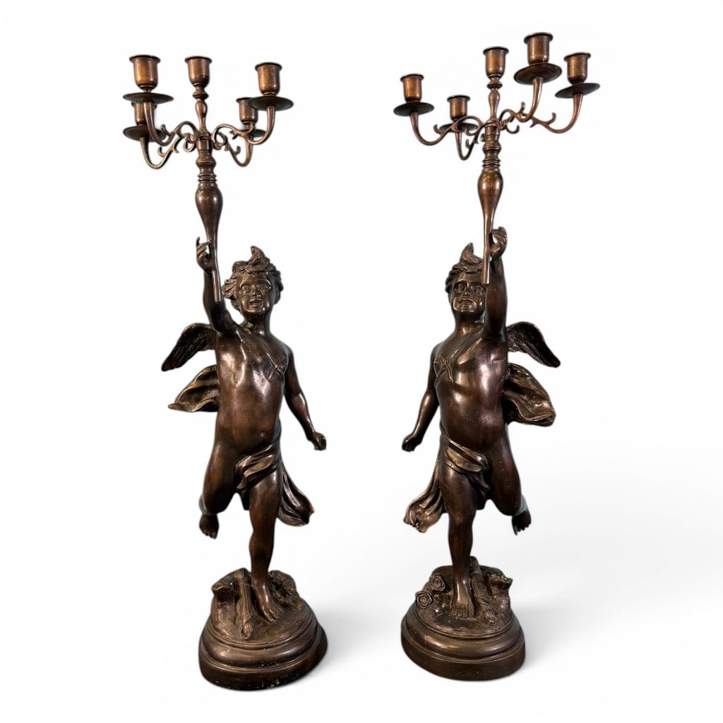 Pair Patinated Bronze Figural Putti Candelabra: Pair of patinated bronze figural candelabra, late 19th/early 20th century, each modeled as a winged putto/cupid standing on a naturalistic base and holding aloft a five-light candelabrum. Each figure 
