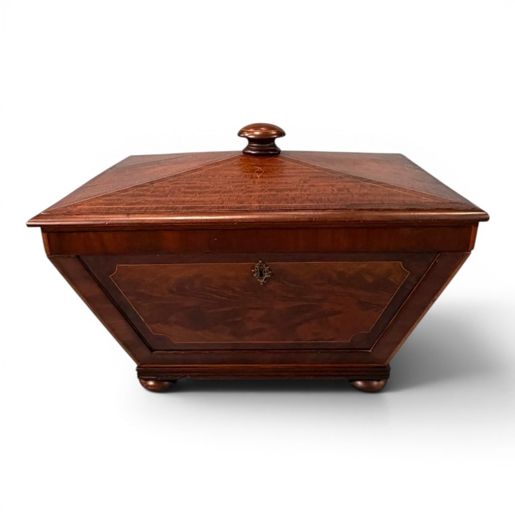 English Regency Mahogany and Inlaid Cellarette, early 19th century: An attractive English Regency mahogany cellarette of sarcophagus form, the hinged pyramidal lid centered by a turned knop and decorated with fine line inlay and stylized geometric inlaid motifs. The