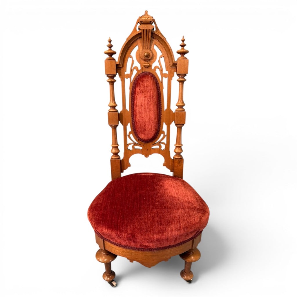 Victorian High-Back Childs Chair with Cranberry Velvet Upholstery: A Victorian high-back childs chair, 19th century, in a light oak or mixed hardwood finish, having an elaborate openwork Gothic-style crest and back with turned side supports, finials, and carved