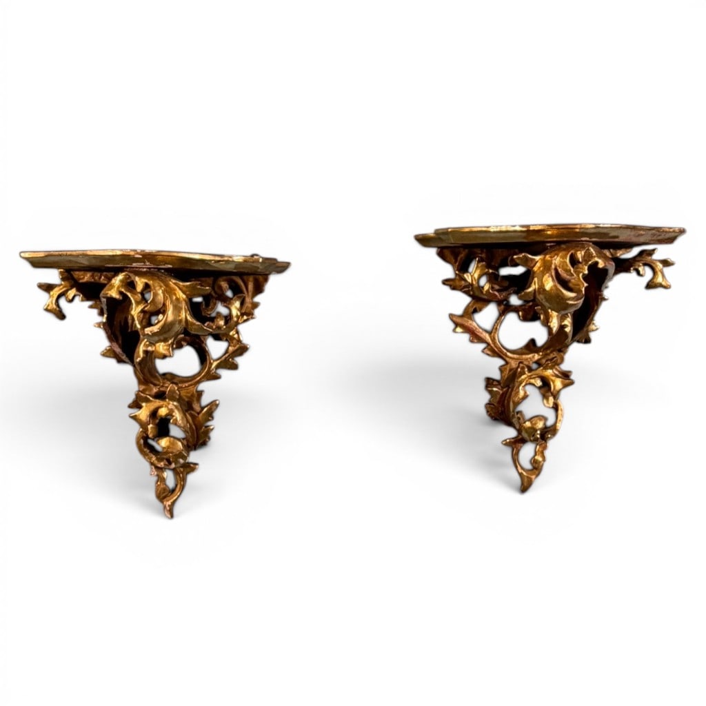 Pair Italian Gilt Rococo Wall Brackets: Pair of Italian Rococo style gilt wall brackets or display sconces, each with shaped demilune shelf above pierced foliate and acanthus scroll supports. The brackets feature richly modeled gilt