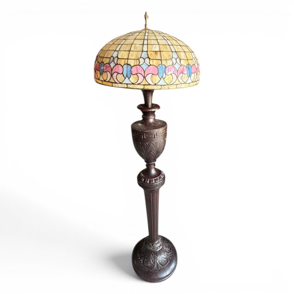 Carved Wood Slag Glass Floor Lamp, Early 20th Century: Carved wood floor lamp, early 20th century, with large domed slag glass shade fitted with warm caramel, cream, pale blue, rose, and lavender panels in a geometric floral border. The tall dark-stained