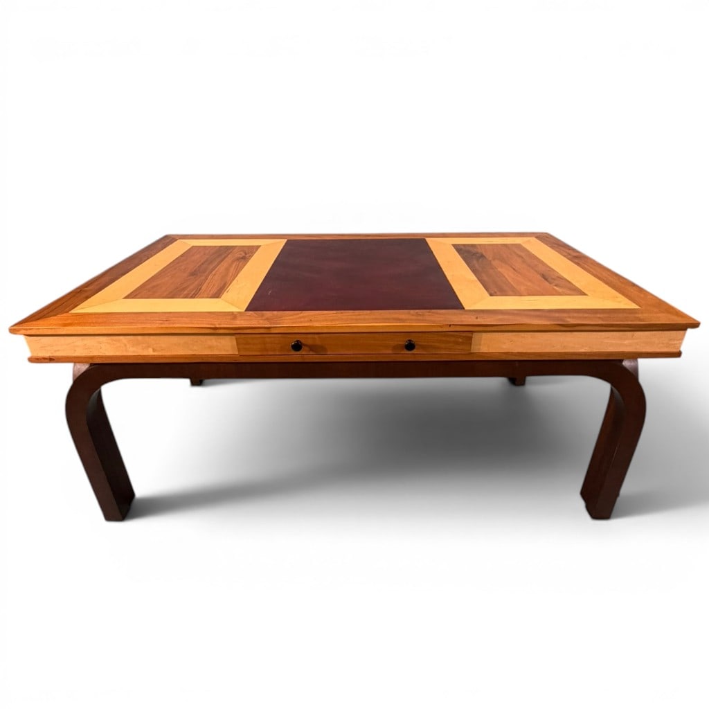Modern Studio-Made Writing Desk, Mid-20th Century Style: A modern studio-made writing desk in a mid-century inspired form, having a large rectangular top with paneled mixed-wood design and inset burgundy leather or leatherette writing surface, above a