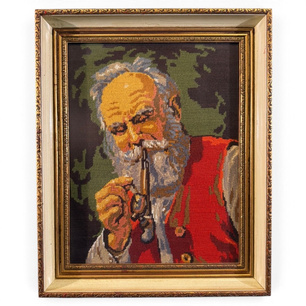 Needlepoint Portrait of Gentleman with Pipe: Framed needlepoint portrait of an elderly bearded gentleman holding a pipe, depicted in red garment against a dark ground, mounted under glass in a molded gilt and painted frame. Measures 22 in. H x