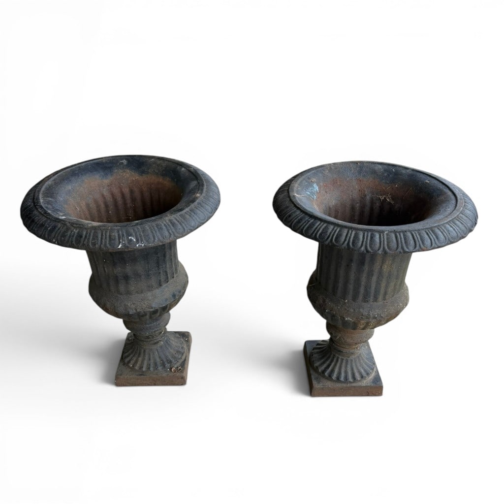 Pair of Cast Iron Garden Urns: Pair of cast iron garden urns, each in the classical campana form with flared gadrooned rim, fluted body, lower molded knop, and square plinth base. The pair retains an old dark painted surface with