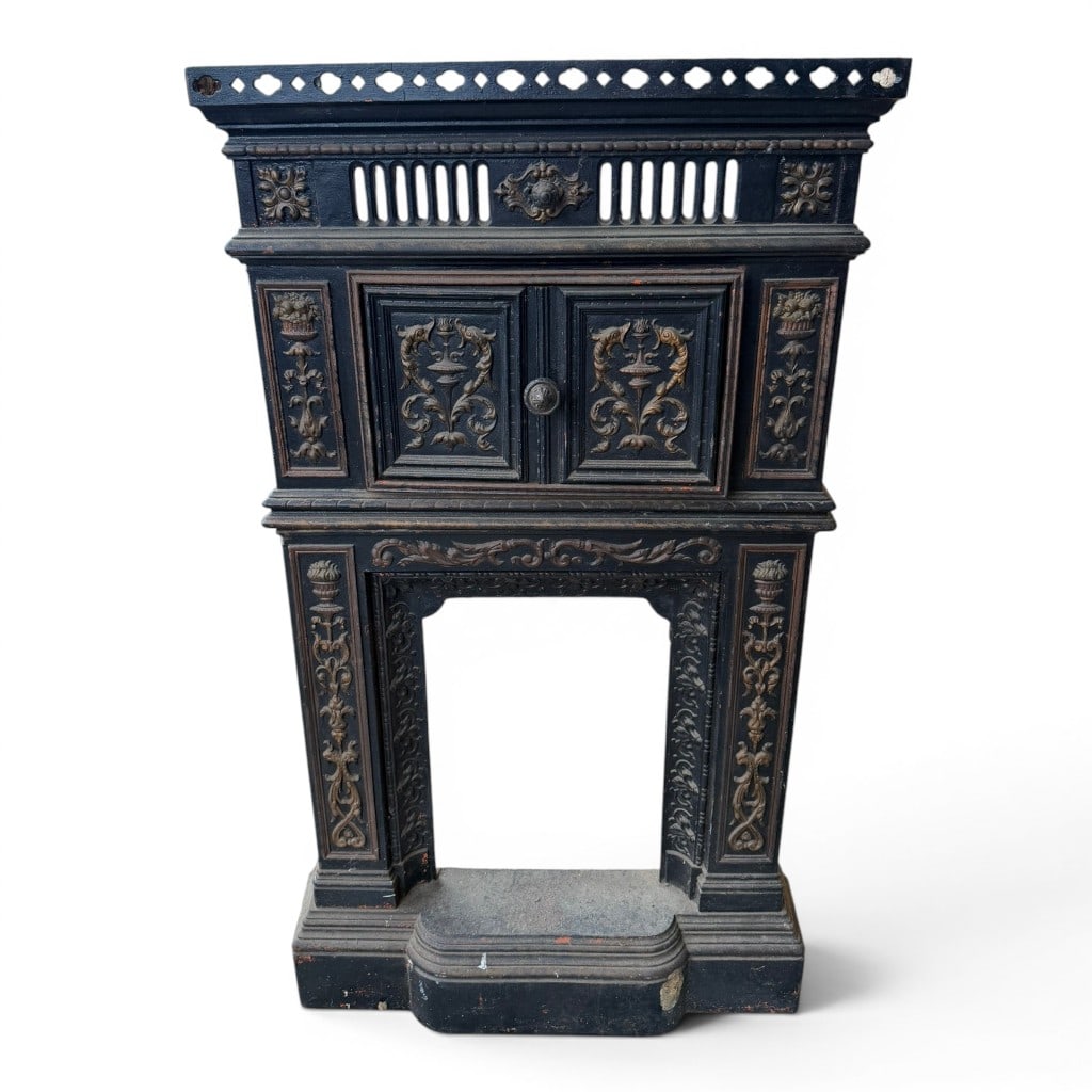 Classical Cast Iron Fireplace Mantel: Classical cast iron fireplace mantel, late 19th to early 20th century, with black painted surface and gilt highlighted relief ornament, the upper cabinet section with paneled double doors and urn, ant