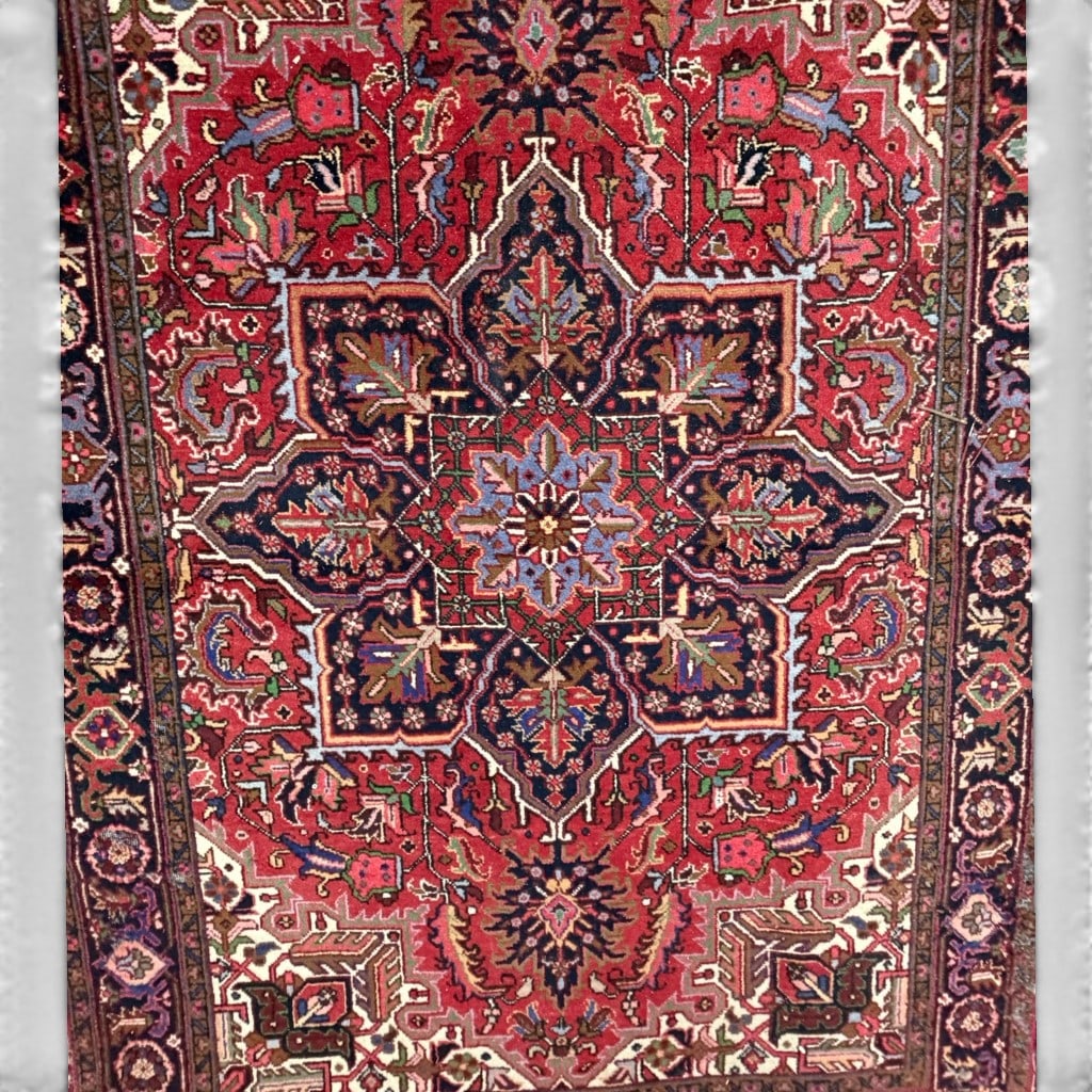 Hand Knotted Heriz Wool Rug, 11 ft 1 in x 7 ft 6 in: Hand knotted Heriz wool rug, having a red field with large geometric central medallion, angular foliate devices, ivory corner spandrels, and a dark blue border with stylized floral and vine